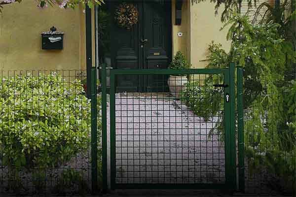 Acceso a entrada de casa desde una puerta de jardín, formado por malla metálica